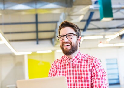 Man in bright office space working on laptop